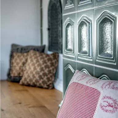 Cozy cushions are lying on a wooden floor. In the background, decorative tiles are visible.