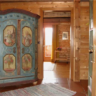 A cozy hallway with an artistically painted closet and wood paneling. In the background, more furniture and a window are visible.