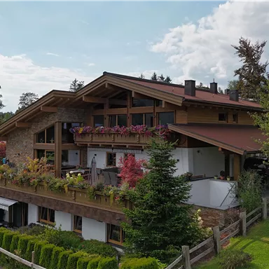 A beautiful house in alpine style with a large balcony.  
Surrounded by green meadows and trees.