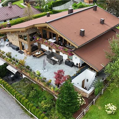 A beautiful house with a large garden and a terrace. The surroundings are green and well-maintained.