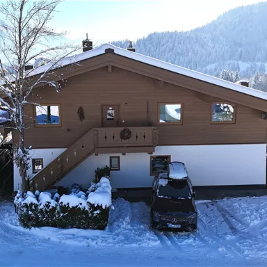 A cozy wooden house in the snow with a beautiful surrounding landscape. The temperatures are cold, and the area is covered with a thick layer of snow.