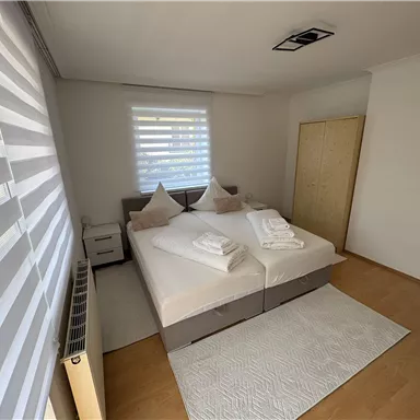 A modern bedroom with a double bed and white bed linens.  
Large windows provide plenty of daylight and a bright, friendly atmosphere.