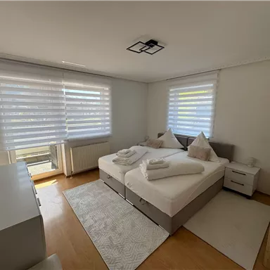 A modern bedroom with two single beds and bright curtains. The clean furnishings create an inviting atmosphere.