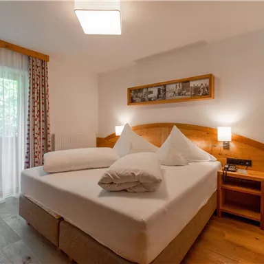 A cozy bedroom with a large double bed and two pillows. Large windows provide plenty of daylight.