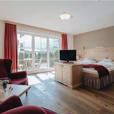 A cozy room with a double bed and a television.
Large windows let in plenty of light and offer a view of the balcony.