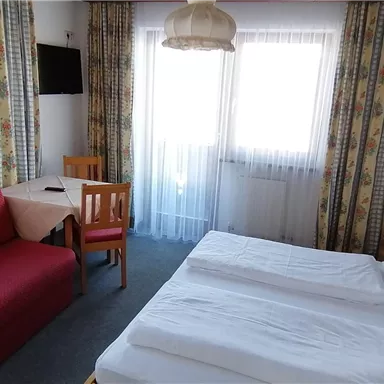 A cozy room with a double bed and a red sofa.
Large windows provide plenty of natural light.