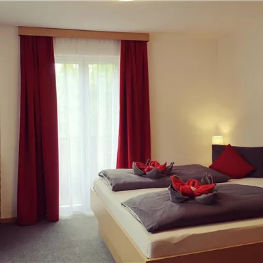 A cozy room with two single beds and red curtains. The elegant decor creates an inviting atmosphere.