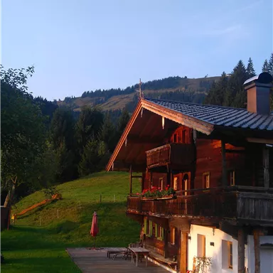 Ein charmantes Holzhaus in malerischer Landschaft. Über dem Haus schwebt ein Heißluftballon in einem klaren Himmel.