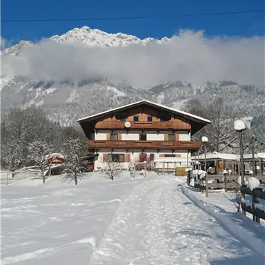 Ein schönes Gebäude im Schnee mit Bergen im Hintergrund. Der klare blaue Himmel ergänzt die winterliche Landschaft.