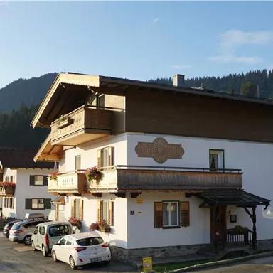 A charming building in the Alps with a beautiful wooden balcony. Surrounded by green meadows and mountains.