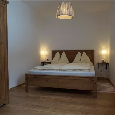 Ein gemütliches Schlafzimmer mit einem Doppelbett und zwei Nachttischen. Der Raum hat warme Holzdetails und sanftes Licht.