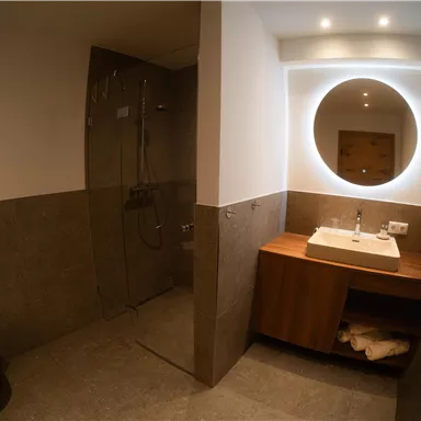 Ein modernes Badezimmer mit Dusche und Waschbecken. Die Wände sind in neutralen Farben gehalten und es gibt eine gemütliche Atmosphäre.