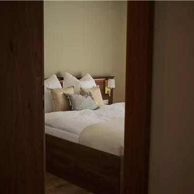 Ein gemütliches Schlafzimmer mit einem großen Bett und vielen Kissen. Die Wände sind in sanften Farben gehalten und es gibt natürliches Licht.