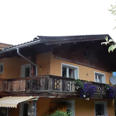 A cozy house with a balcony and flower boxes. The facade is painted in warm colors.