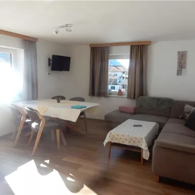 A bright living space with a cozy sofa and a table. Large windows provide plenty of daylight.