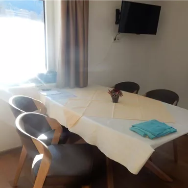 A cozy dining area with a table and chairs. Light streams into the room through the window.
