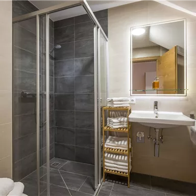 A modern bathroom with a shower and a sink. There are fresh towels and a stylish interior design.
