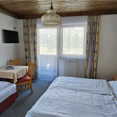 A cozy bedroom with two beds and an additional sofa bed.
Large windows provide plenty of light and a view outside.