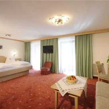 A cozy hotel room with two beds and a beautiful view. The room is bright and friendly decorated, with a small table and a sofa.