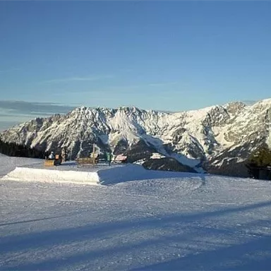 A beautiful, snow-covered mountain with a clear blue sky. The landscape offers a calm and idyllic winter atmosphere.