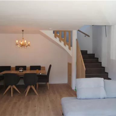 Ein modernes Wohnzimmer mit einem bequemen Couch und einem Essbereich. Eine Treppe führt in den oberen Bereich des Raumes.