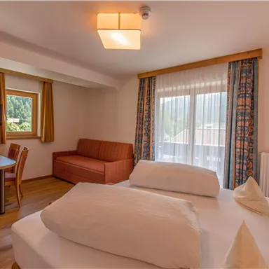 A cozy room with a double bed and a seating area. Large windows provide plenty of daylight and a beautiful view.