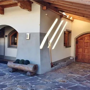 Ein modernes Haus mit einem Holzdach und einer rustikalen Eingangstür. Der Eingangsbereich ist mit Steinpflaster und einem Holzbank dekoriert.