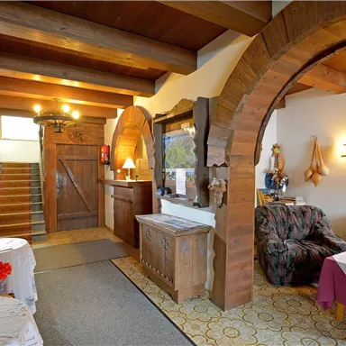 An inviting lobby with a wooden beam ceiling and cozy furniture. Stairs and decorative elements can be seen in the background.