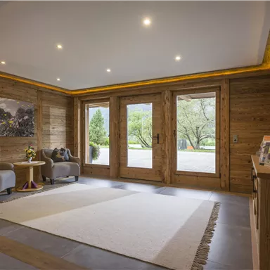 An inviting entrance area with wooden walls and modern furniture. Large windows provide a view of the outdoor area.