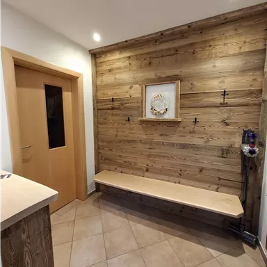 An inviting hallway with wooden paneling and a seating area. The walls are light, and the lighting is warm and friendly.