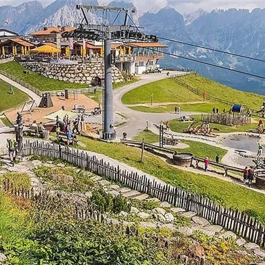 A picturesque mountain landscape with a cable car and a restaurant. Many people are enjoying the view and outdoor activities.