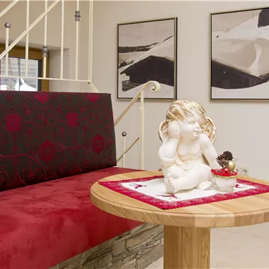 A cozy reception area with a red sofa and a wooden table. On the table sits an elegant statue of an angel.