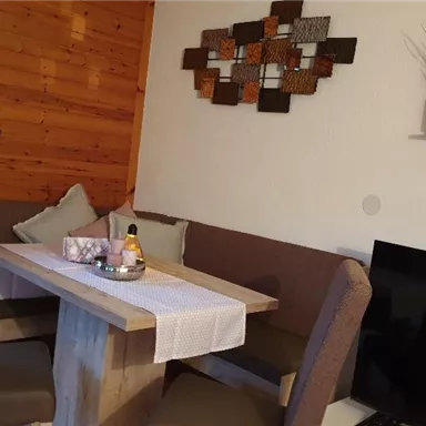 An inviting dining area with a wooden table and comfortable chairs. The walls are designed to look like wood, and decorative elements complete the cozy atmosphere.