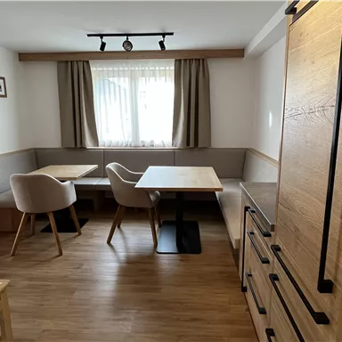 A cozy dining area with wooden design and modern chairs. Large windows provide plenty of natural light.