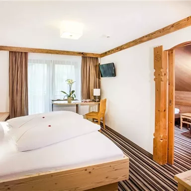 Ein geräumiges Hotelzimmer mit Holzmöbeln und zwei Betten. Der Raum verfügt über ein Fenster mit Blick auf einen kleinen Tisch und Fernseher.