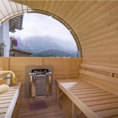 A cozy wellness area with wood paneling and a view of the mountains. Towels and a bucket create a relaxing atmosphere.