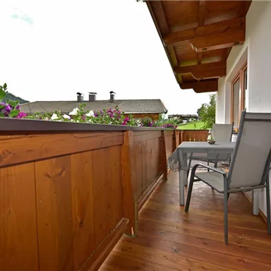 A cozy balcony with wooden cladding and a view of nature. A table and a chair invite you to relax.