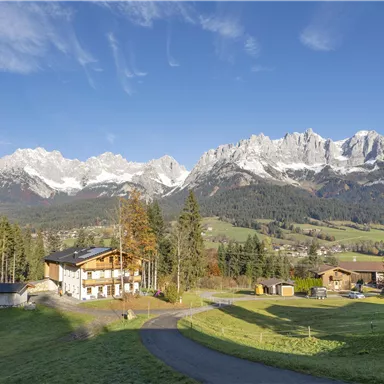 A picturesque landscape with majestic mountains in the background. In the foreground, typical alpine houses and green meadows are visible.
