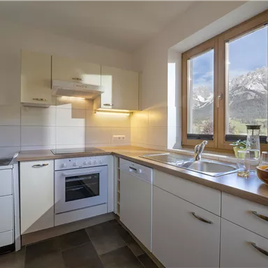 A bright and modern kitchen with a window that offers a view of the mountains. Simple furniture and an inviting atmosphere.