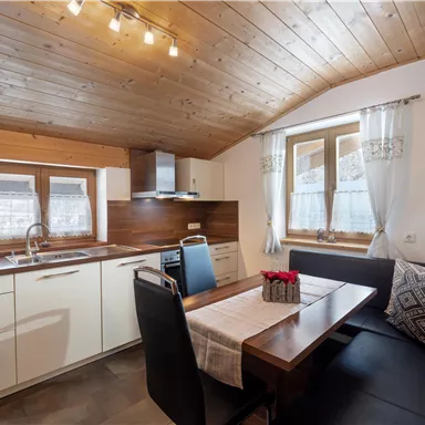 A modern kitchen with wood paneling and a dining area. The warm colors create an inviting atmosphere.