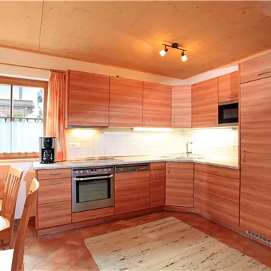 A modern kitchen with wooden cabinets and a bright, welcoming atmosphere. The dining area is cozy, equipped with a table and chairs.