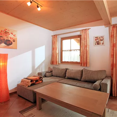 A cozy living room with a gray sofa, a wooden coffee table, and a decorative floor lamp. Large windows with curtains provide bright lighting and create an inviting atmosphere.
