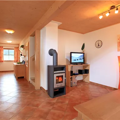 A cozy living space with a wood stove and a television. The walls are light, and there are appealing decorations and lighting.