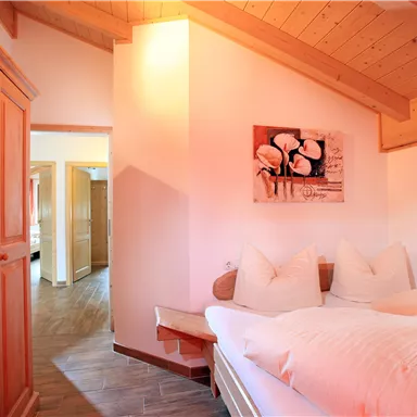 Ein gemütliches Schlafzimmer mit einem Holzkleiderschrank und einer warmen Holzdecke. Das Zimmer ist hell und einladend, mit einem Bild an der Wand.