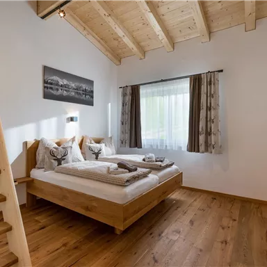 A cozy bedroom with a double bed and wooden shelf. Large windows provide plenty of light and a pleasant atmosphere.