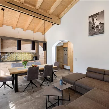 A modern, bright living room with an open kitchen area. Wooden details and an inviting atmosphere create coziness.