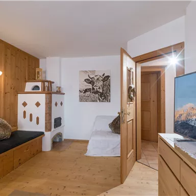A cozy room with wood paneling and a sofa. On a table stands a television, and on the wall hangs a piece of artwork.