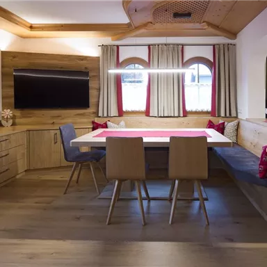 Ein modernes Wohnzimmer mit Holzverkleidungen. Es gibt einen esstisch und eine gemütliche Sitzecke.