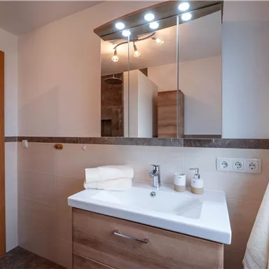 Ein modernes Badezimmer mit Holzverkleidungen und einem stilvollen Waschbecken. Die Beleuchtung sorgt für eine angenehme Atmosphäre.