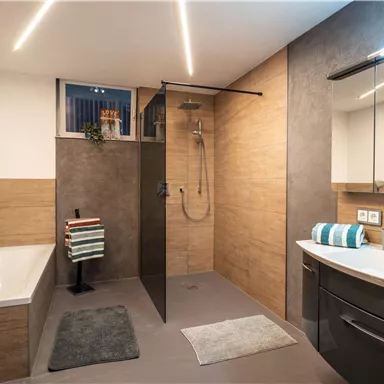 Ein modernes Badezimmer mit einer Dusche und einer Badewanne. Die Wände sind in neutralen Tönen gehalten, ergänzt durch stilvolle Accessoires.